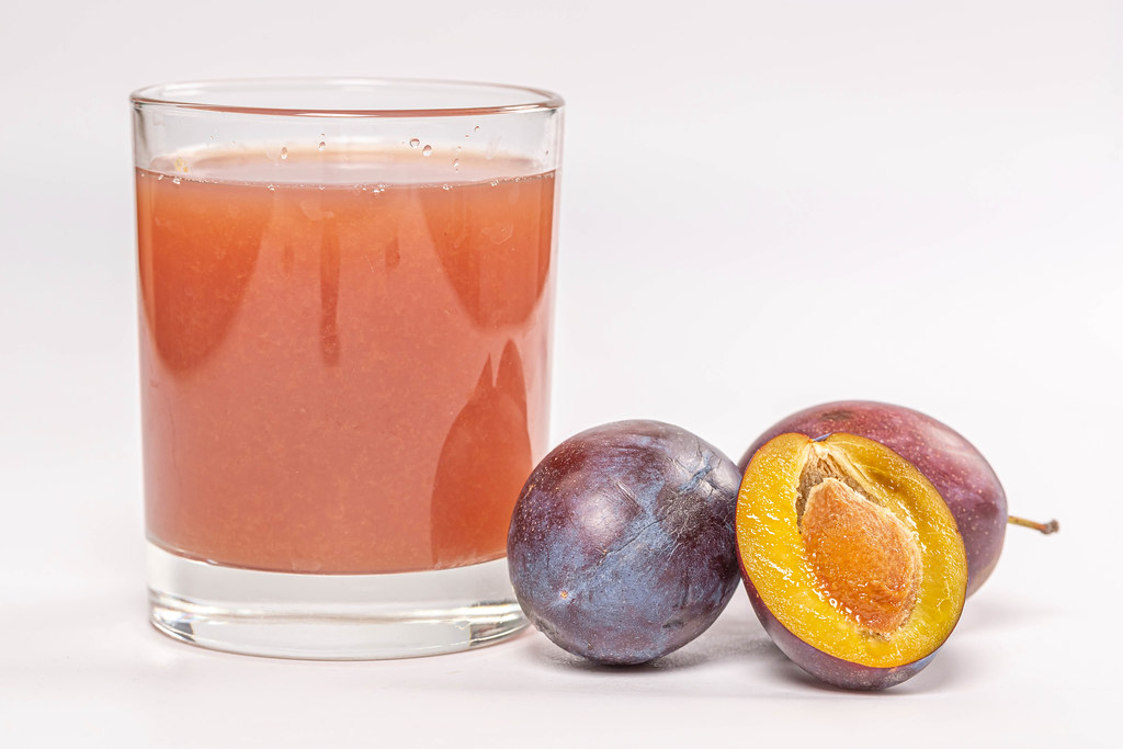 A glass of fresh plum juice with fresh ripe plums A glass of fresh plum juice with fresh ripe plums