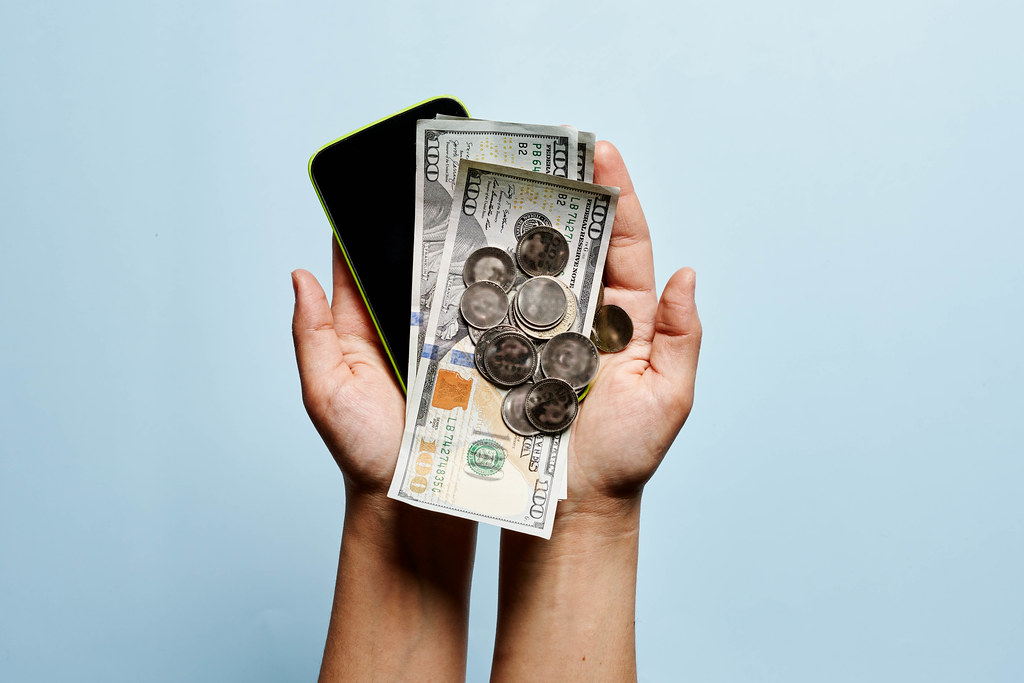 A person holding mobile phone and money A person holding mobile phone and money