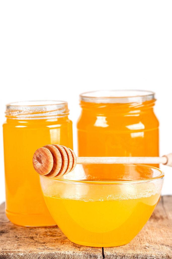 Background with natural bee honey in glass jars and a bowl Background with natural bee honey in glass jars and a bowl