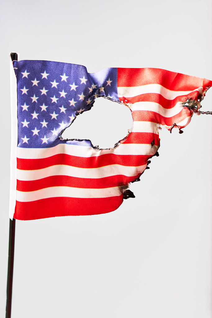 Burned US national flag against bright background Burned US national flag against bright background