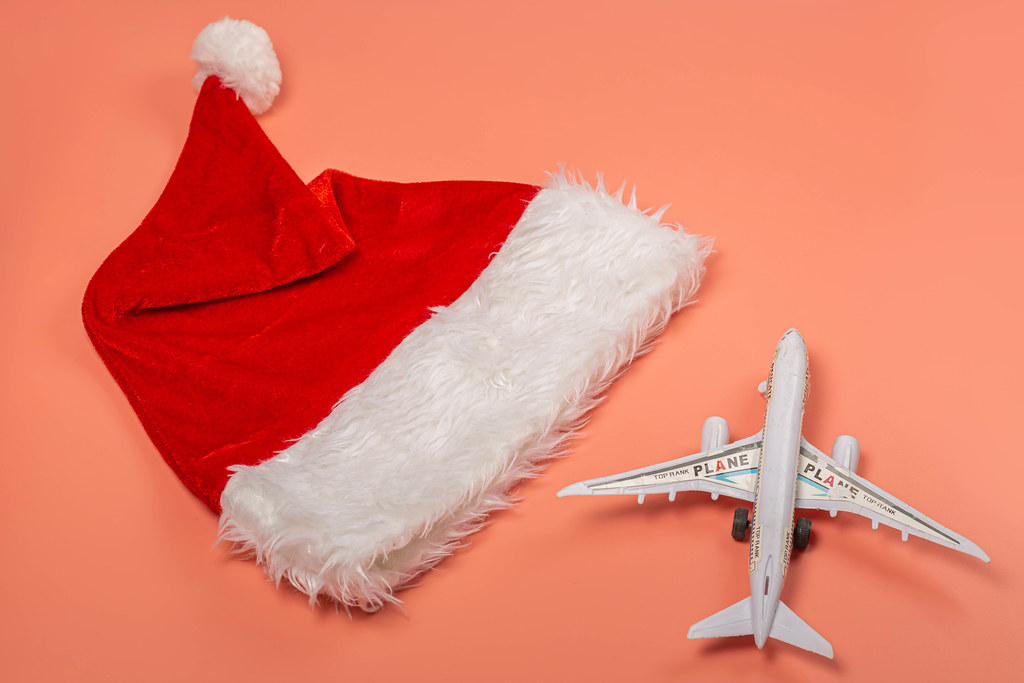 Christmas travel concept - santa hat and airplane on pink background Christmas travel concept - santa hat and airplane on pink background