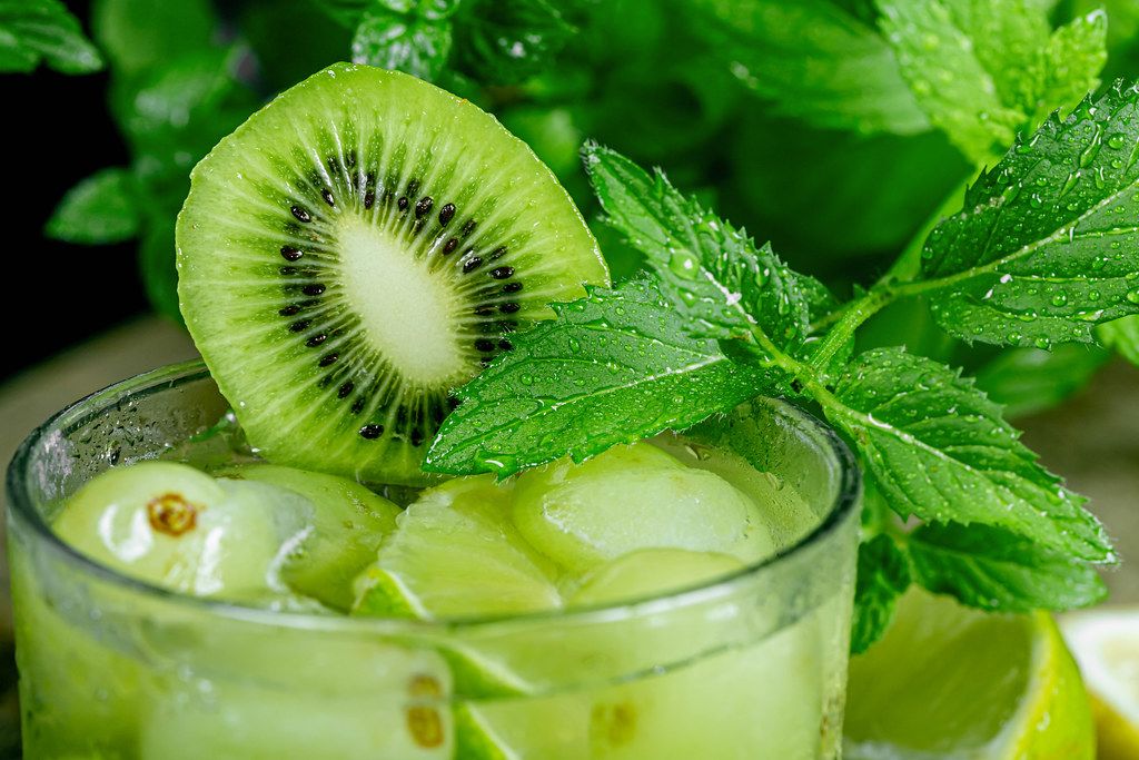 Close-up, a glass of cocktail with green fruit and fresh mint Close-up, a glass of cocktail with green fruit and fresh mint