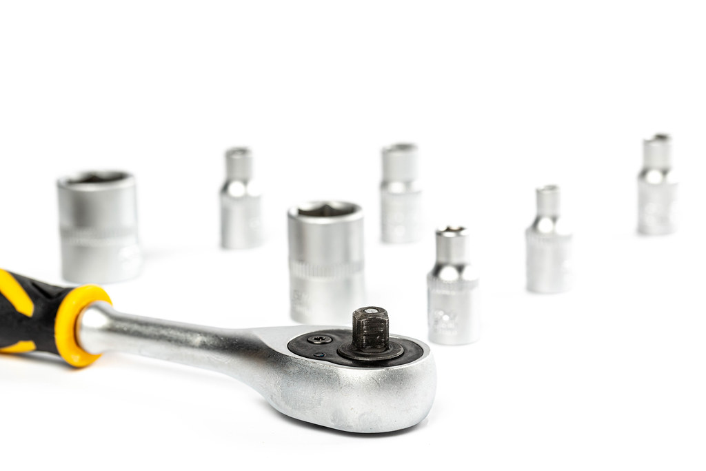 Close-up, ratchet wrench on white background with ratchet sockets behind Close-up, ratchet wrench on white background with ratchet sockets behind