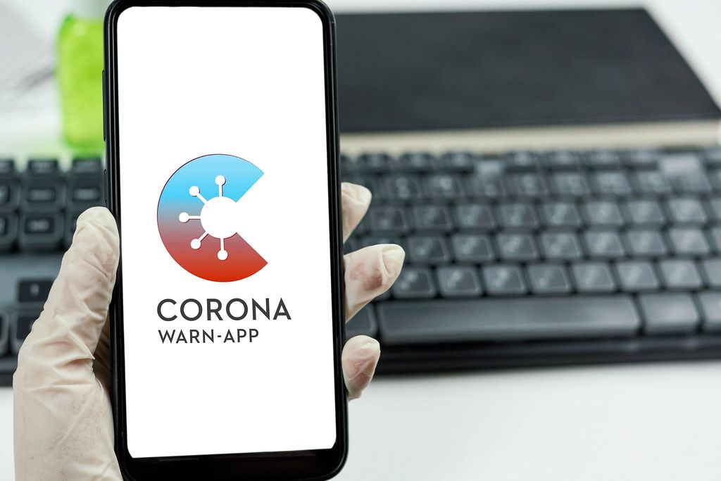 Doctor holding a smartphone with Corona warn-app that helps trace infection chains of SARS-CoV-2 or COVID-19 in Germany Doctor holding a smartphone with Corona warn-app that helps trace infection chains of SARS-CoV-2 or COVID-19 in Germany