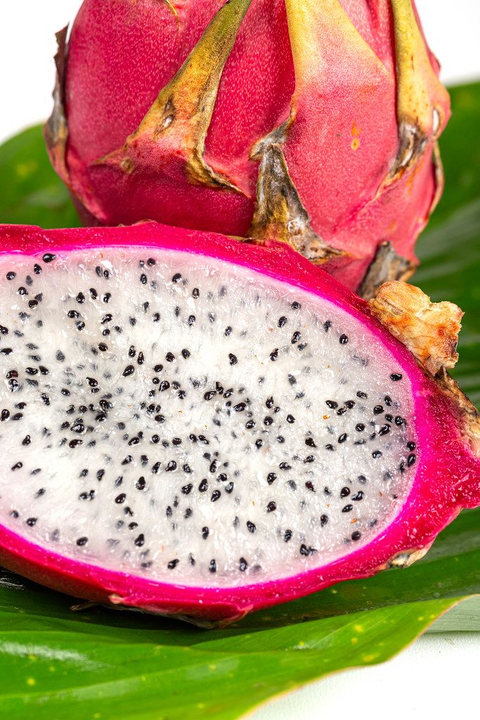 Fresh ripe dragon fruit on green wet leaf Fresh ripe dragon fruit on green wet leaf