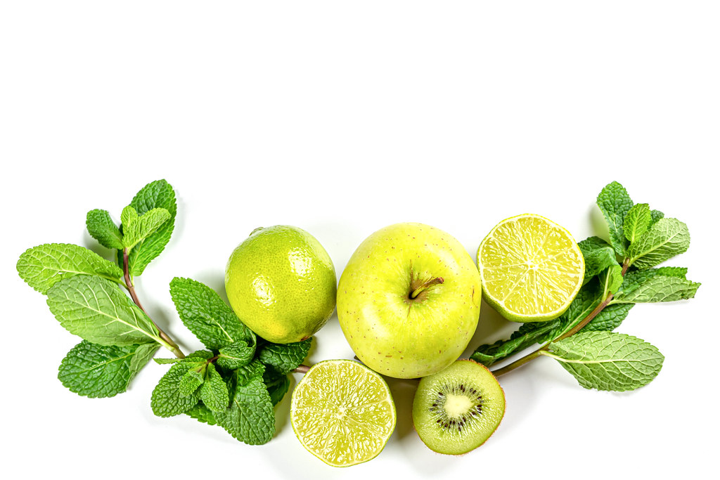 Green fruits and sprigs of mint on white, top view Green fruits and sprigs of mint on white, top view