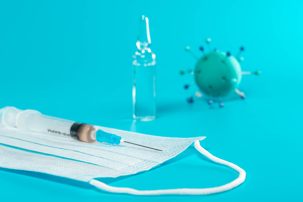 Medical mask with syringe, ampoule and abstract virus model on blue background Medical mask with syringe, ampoule and abstract virus model on blue background