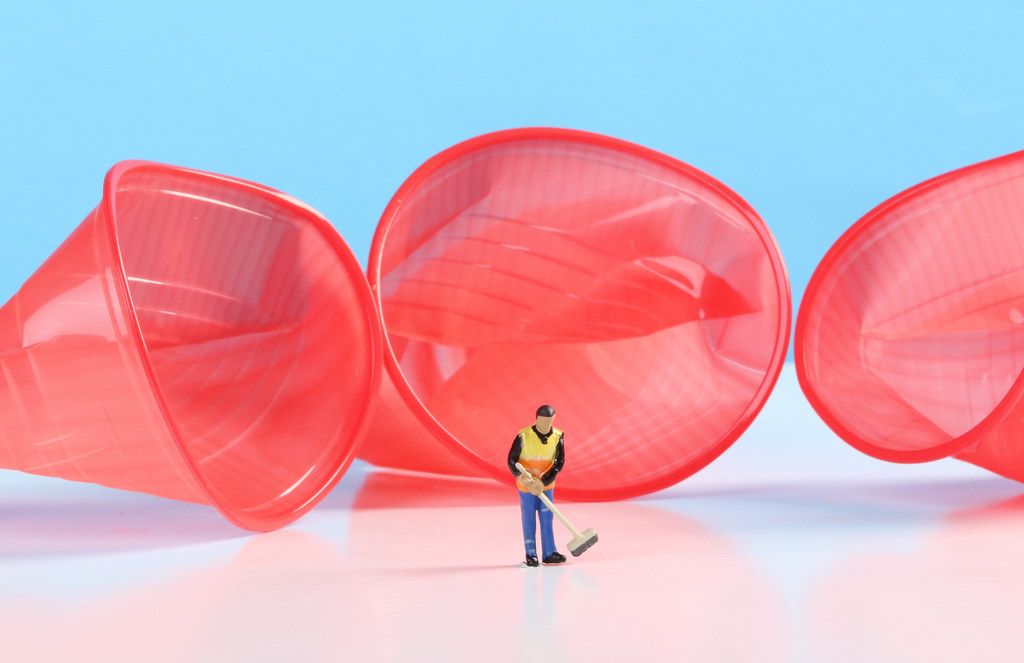 Miniature cleaning worker with empty plastic cups Miniature cleaning worker with empty plastic cups