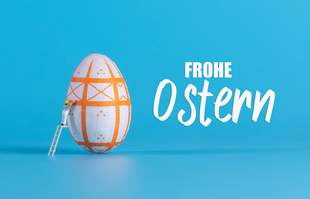 Miniature painter painting easter egg and Frohe Ostern text Miniature painter painting easter egg and Frohe Ostern text