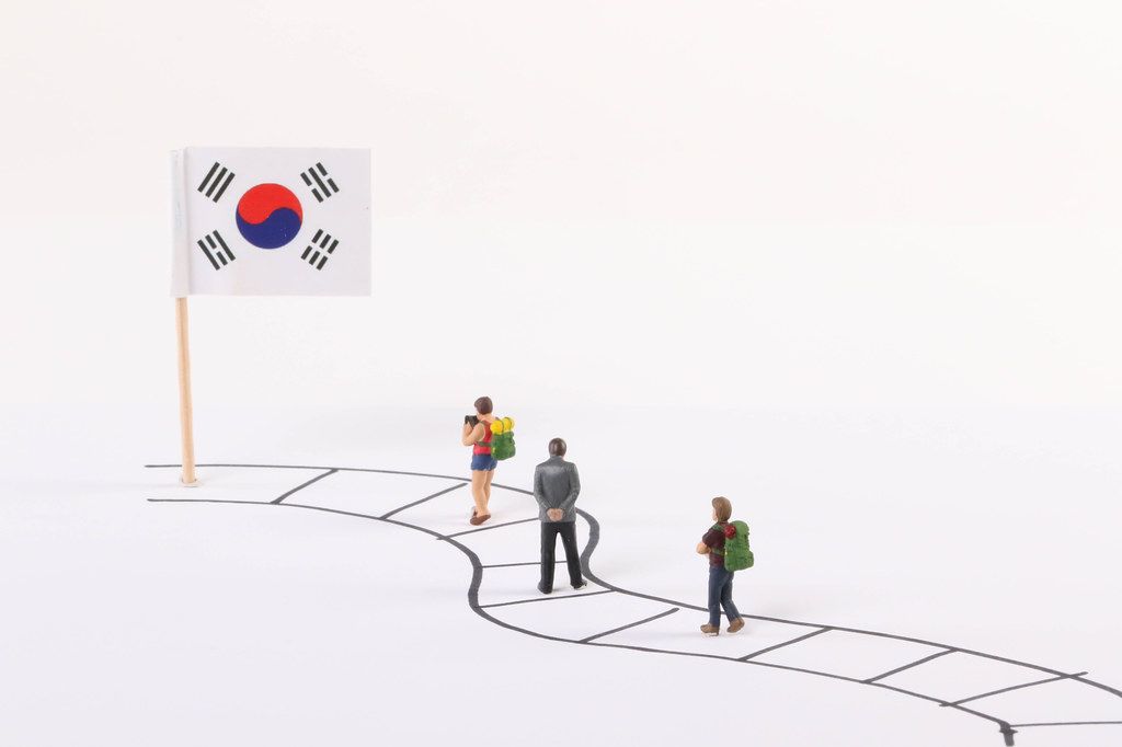 Miniature people walking on a path to the flag of South Korea Miniature people walking on a path to the flag of South Korea