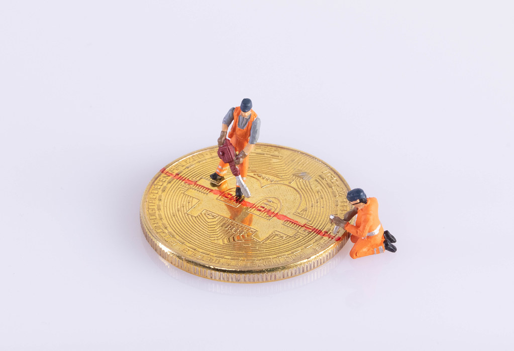 Miniature workers cutting Bitcoin Miniature workers cutting Bitcoin