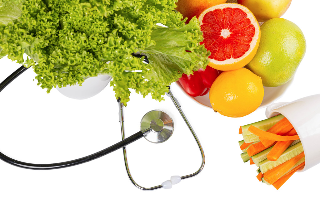 Organic fresh fruits and vegetables with stethoscope on white background Organic fresh fruits and vegetables with stethoscope on white background