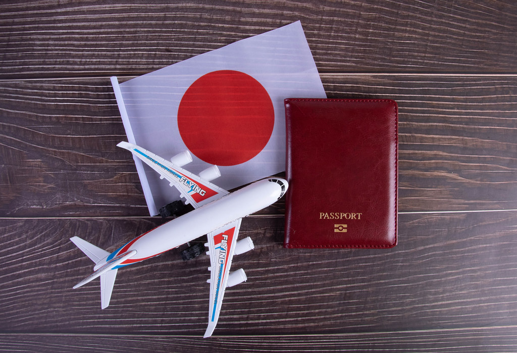 Passport, miniature airplane and flag of Japan on wooden table Passport, miniature airplane and flag of Japan on wooden table