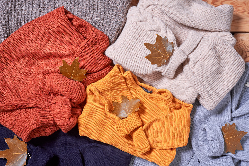pile of knitted sweaters and fall leaves pile of knitted sweaters and fall leaves
