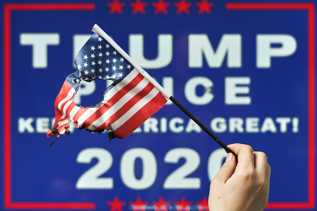 Pro-Trump banner and supporter with a torn American flag Pro-Trump banner and supporter with a torn American flag