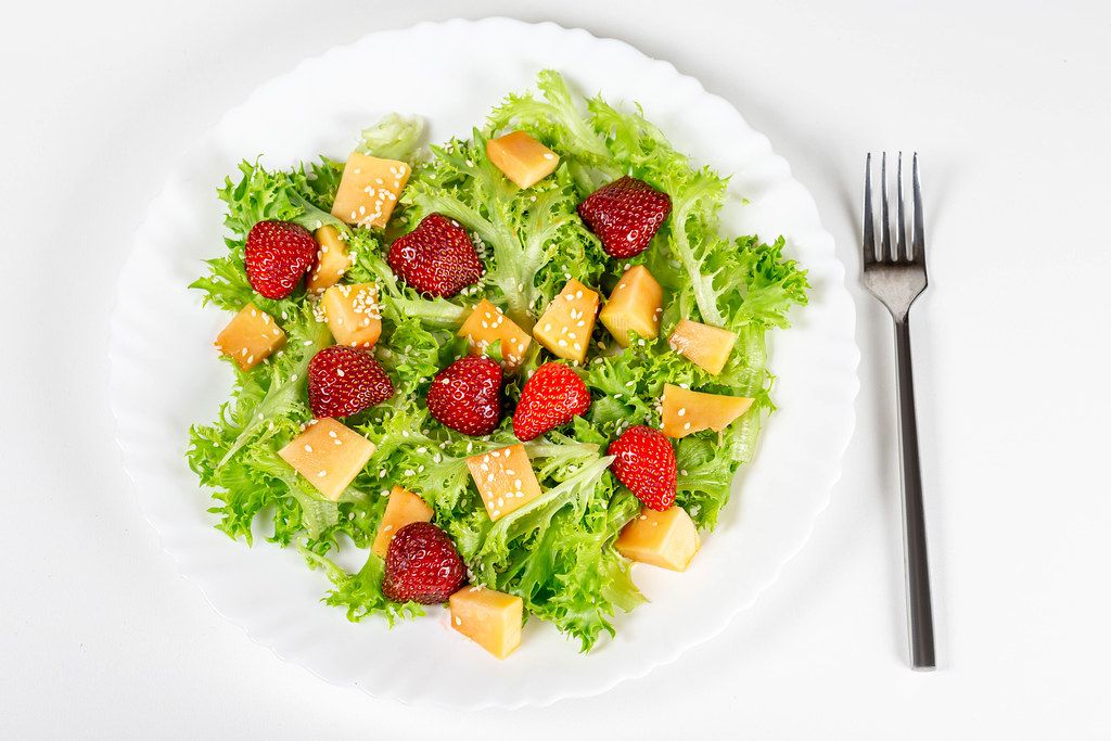 Salad with strawberries, mango, lettuce and sesame seeds. Top view Salad with strawberries, mango, lettuce and sesame seeds. Top view