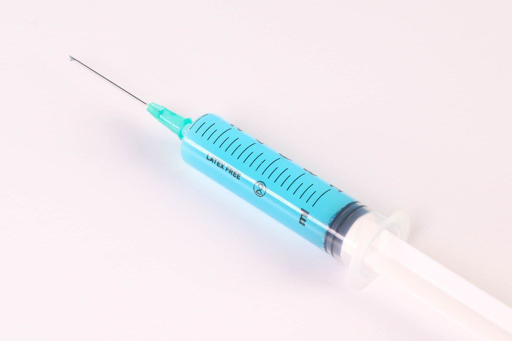 Syringe with blue fluid on white background Syringe with blue fluid on white background