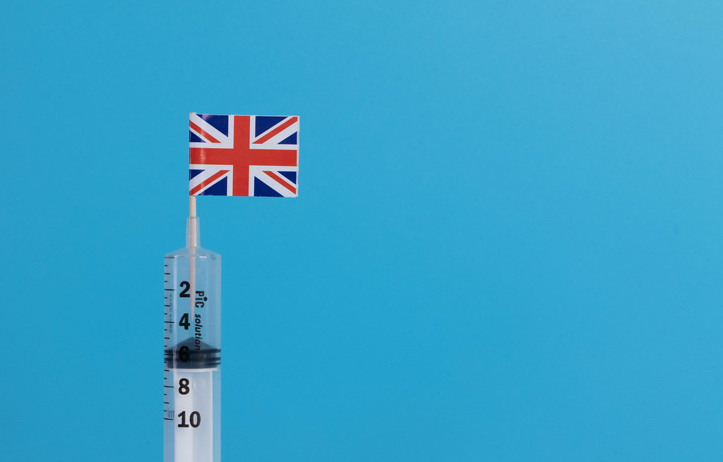 Syringe with flag of UK on blue background Syringe with flag of UK on blue background