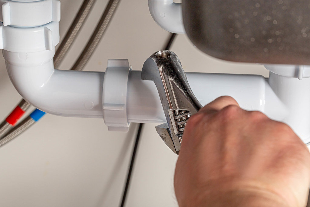 The plumber makes measurements of the diameter of the pipe using an adjustable wrench, close-up The plumber makes measurements of the diameter of the pipe using an adjustable wrench, close-up
