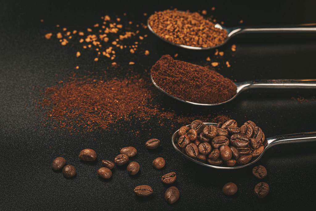 Three spoons of coffee with Soluble coffee, coffee beans and ground coffee on dark background Three spoons of coffee with Soluble coffee, coffee beans and ground coffee on dark background