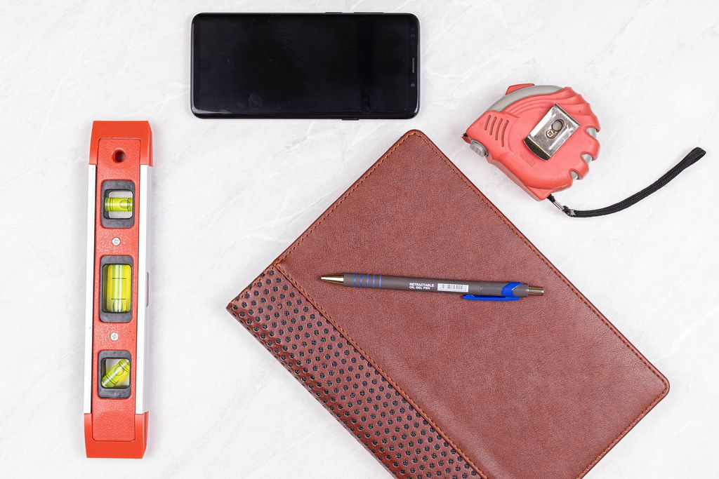 Top view Level Measure Tape Mobile phone Pencil and Paper Notebook Top view Level Measure Tape Mobile phone Pencil and Paper Notebook