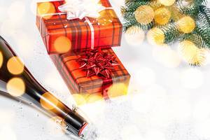 A bottle of champagne and Packed gifts on the background of snow, bokeh with branches of the Christmas tree A bottle of champagne and Packed gifts on the background of snow, bokeh with branches of the Christmas tree