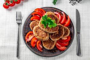 A top view of a dish of fried meat cutlets with a knife and fork A top view of a dish of fried meat cutlets with a knife and fork