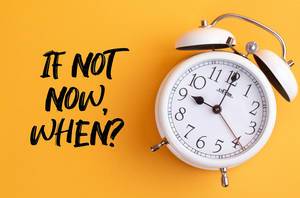 Alarm clock with handwritten text If Not Now, When? on yellow background Alarm clock with handwritten text If Not Now, When? on yellow background