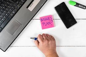 Business Plan concept with lap top hand and mobile phone on the table Business Plan concept with lap top hand and mobile phone on the table