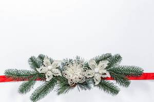 Christmas white background with Christmas tree branches, decor and red ribbon Christmas white background with Christmas tree branches, decor and red ribbon