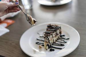 Close Up on the Hand Holding a Piece of Cake on a Fork Close Up on the Hand Holding a Piece of Cake on a Fork