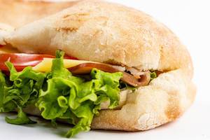 Closeup on Sandwich with Lettuce Cheese Ham and Tomato on white background Closeup on Sandwich with Lettuce Cheese Ham and Tomato on white background