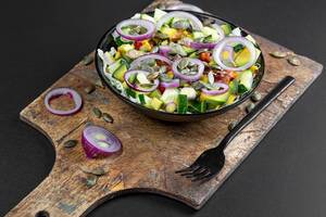 Diet salad with onion, avocado, cucumber and pumpkin seeds on a dark background Diet salad with onion, avocado, cucumber and pumpkin seeds on a dark background