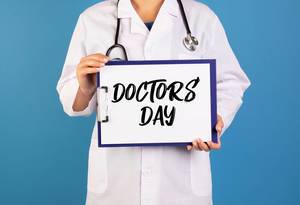 Doctor holding clipboard with Doctors day text Doctor holding clipboard with Doctors day text