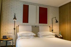 Double bed with white sheets and brick wall in the hotel room of "The Corner Hotel" near the Plaça del Doctor Letamendi Park in Barcelona, Spain Double bed with white sheets and brick wall in the hotel room of "The Corner Hotel" near the Plaça del Doctor Letamendi Park in Barcelona, Spain
