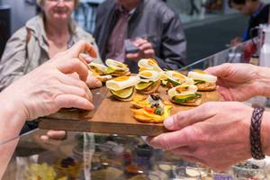 Exhibition chef hands over finger food on a wooden board to IFA fair visitors Exhibition chef hands over finger food on a wooden board to IFA fair visitors