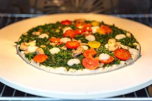 Fleischlose Pizza Verdura der Trattoria Alfredo für Veganer, mit Spinat, Pilzen und gelben Tomaten im Backofen auf dem Pizzastein von BBQ Premium Fleischlose Pizza Verdura der Trattoria Alfredo für Veganer, mit Spinat, Pilzen und gelben Tomaten im Backofen auf dem Pizzastein von BBQ Premium