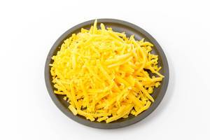 Geriebener Cheddar auf einem schwarzen Teller auf weißem Hintergrund Geriebener Cheddar auf einem schwarzen Teller auf weißem Hintergrund