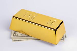 Gold bar on top of the money stack Gold bar on top of the money stack