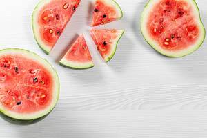 Halves and pieces of watermelon on white wooden background. Top view Halves and pieces of watermelon on white wooden background. Top view