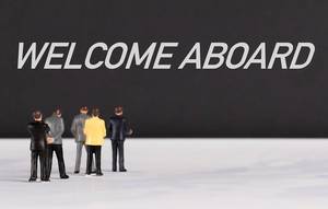 People standing in front of Welcome Aboard text People standing in front of Welcome Aboard text