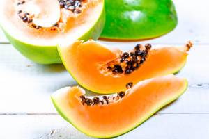 Pieces of fresh ripe papaya on white wooden background Pieces of fresh ripe papaya on white wooden background