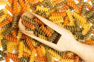 Pile of colorful macaroni with wooden spatula on the top Pile of colorful macaroni with wooden spatula on the top