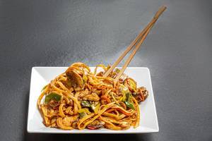 Plate with rice noodles and chopsticks on black background