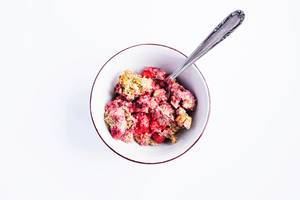 Porridge with pumpkin seeds and Strawberries in a bowl with a spoon on white background Porridge with pumpkin seeds and Strawberries in a bowl with a spoon on white background