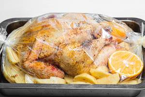 Raw chicken with spices, potatoes and oranges in a baking tray before baking Raw chicken with spices, potatoes and oranges in a baking tray before baking