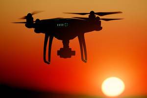 Silhouette of drone at sunset, orange sky Silhouette of drone at sunset, orange sky