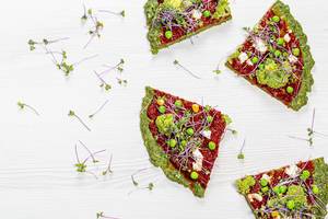 Slices of vegetarian vegetable pizza with micro-green cabbage on a white wooden background. Top view Slices of vegetarian vegetable pizza with micro-green cabbage on a white wooden background. Top view