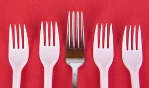 Stainless steel and plastic forks on red background Stainless steel and plastic forks on red background