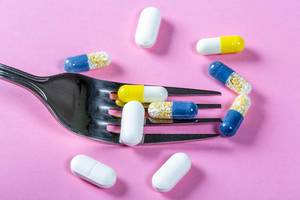 The concept of drug nutrition-encapsulated medicines with a fork on a pink background The concept of drug nutrition-encapsulated medicines with a fork on a pink background